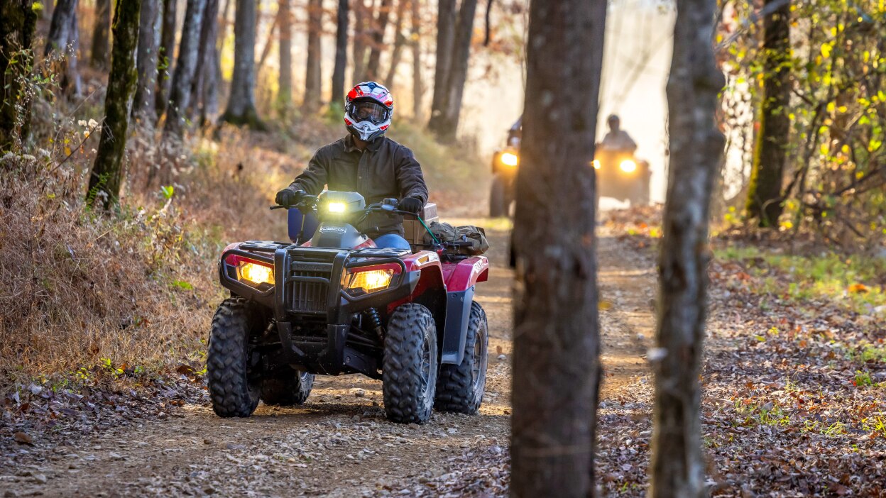 A rider on a forest trail on a Honda Rubicon 700. 