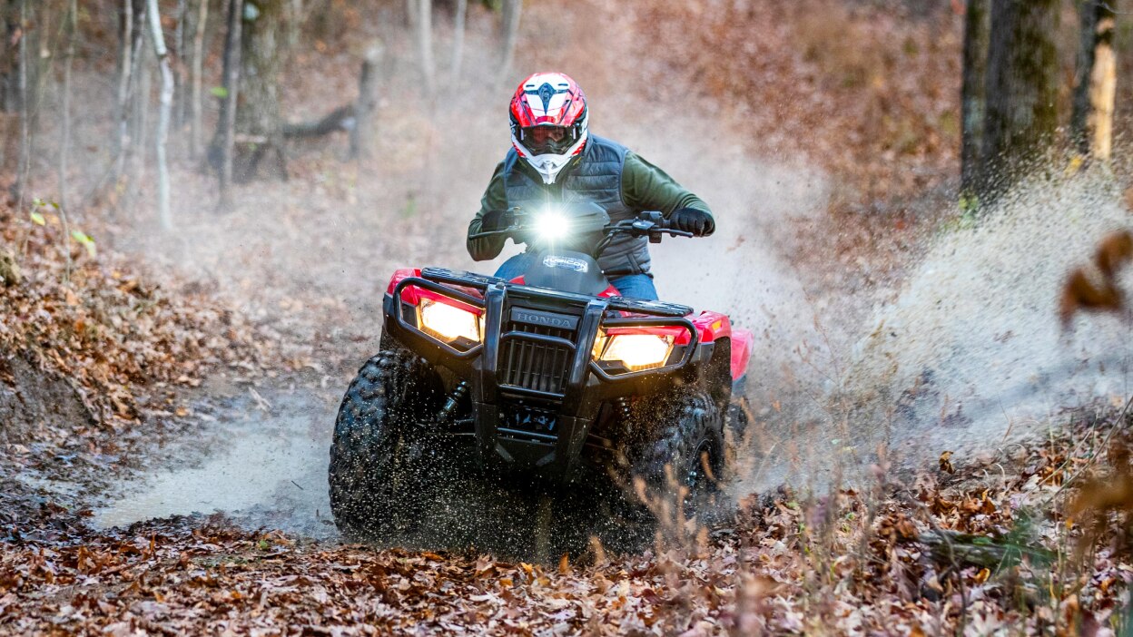A rider on a Honda Rubicon 700 on a leafy trail 