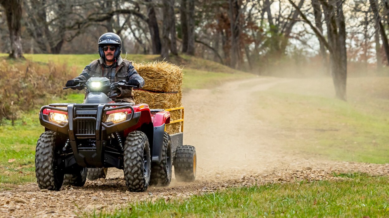 A rider on a Honda Rubicon 700 pulling some hay.