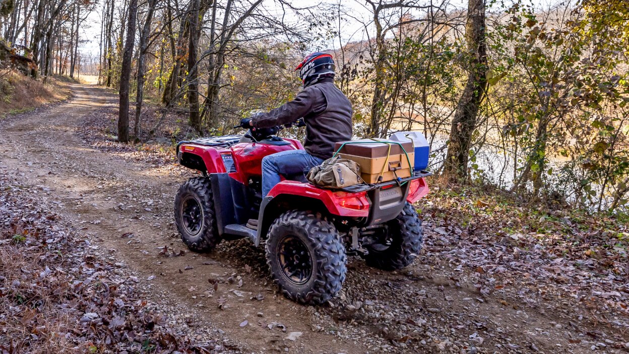 A rider on a Honda Rubicon 700 with some boxes strapped to the back. 