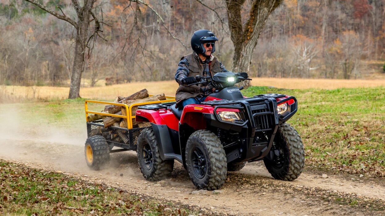 A rider hauling some wood in a trailer on a Honda Rubicon 700 