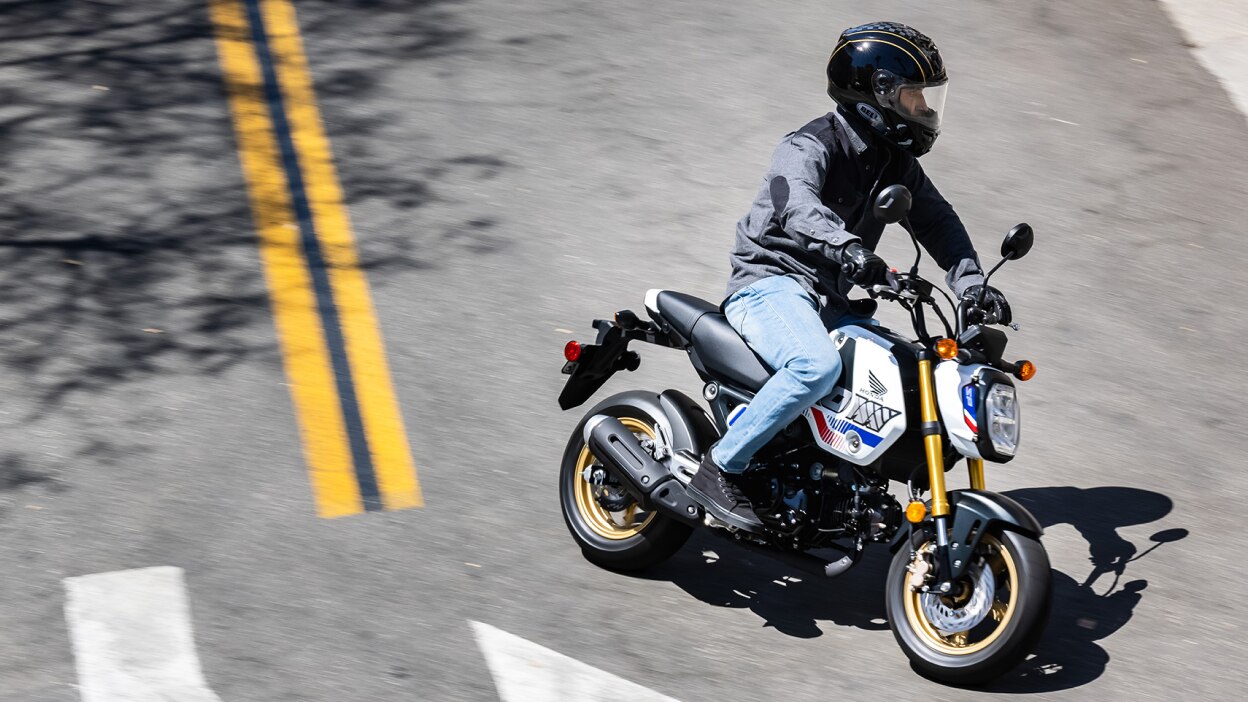 Rider on yellow bike making left turn on road. High angle of road.