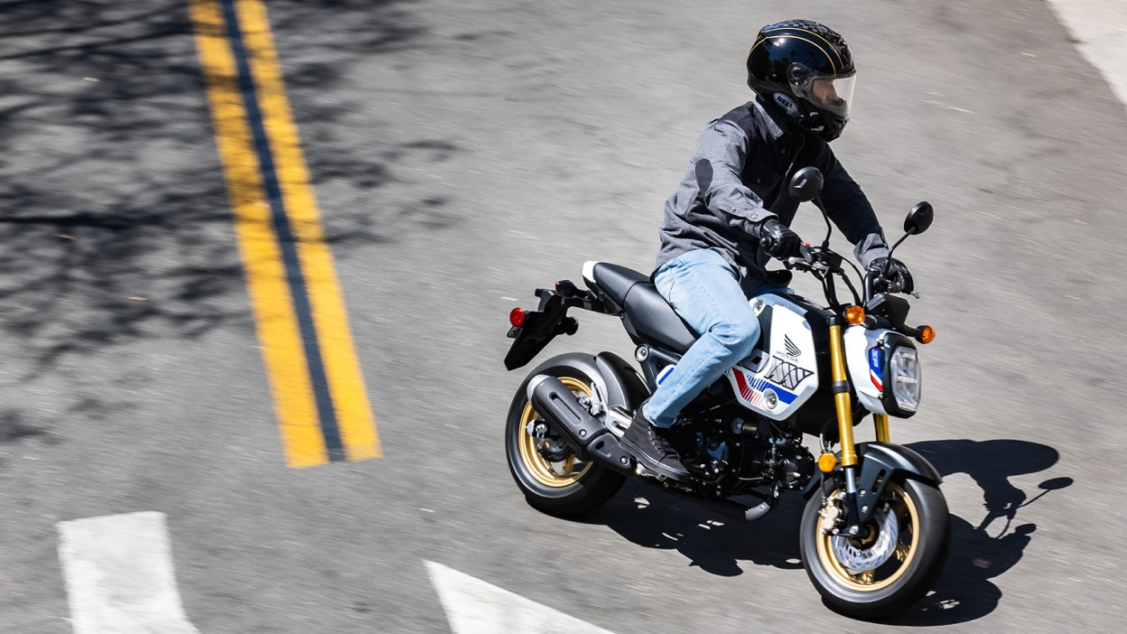 Rider on yellow bike making left turn on road. High angle of road.