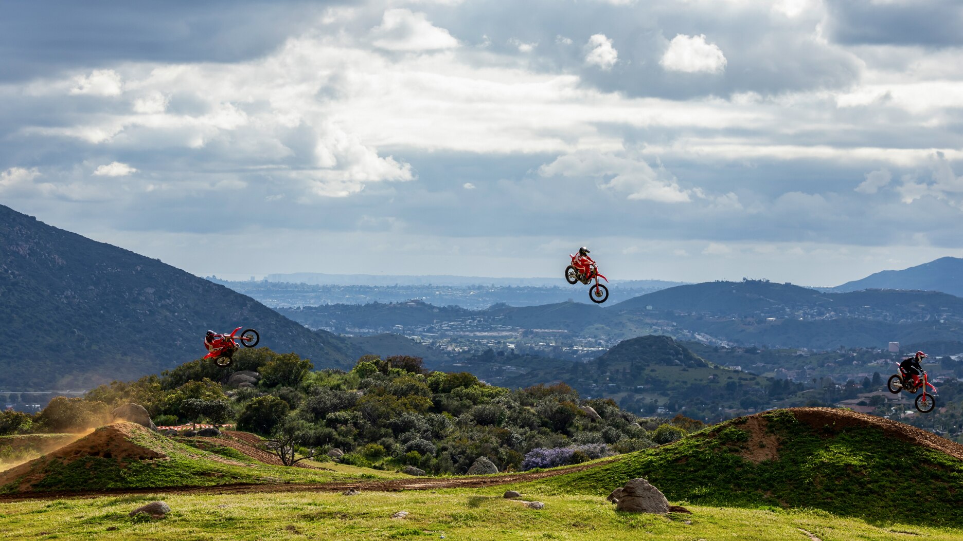 Three riders in air from one hill to next.
