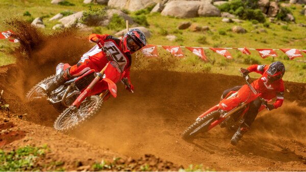 Two riders turning left on dirt track. Lifestyle.