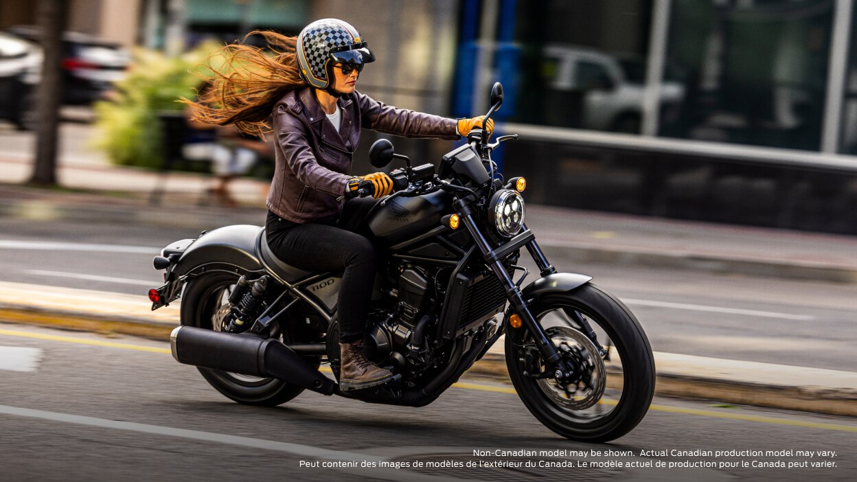 Rider on road going right. Building and sidewalk in background. Non-Canadian model(s) may be shown. Actual Canadian production model(s) may vary.