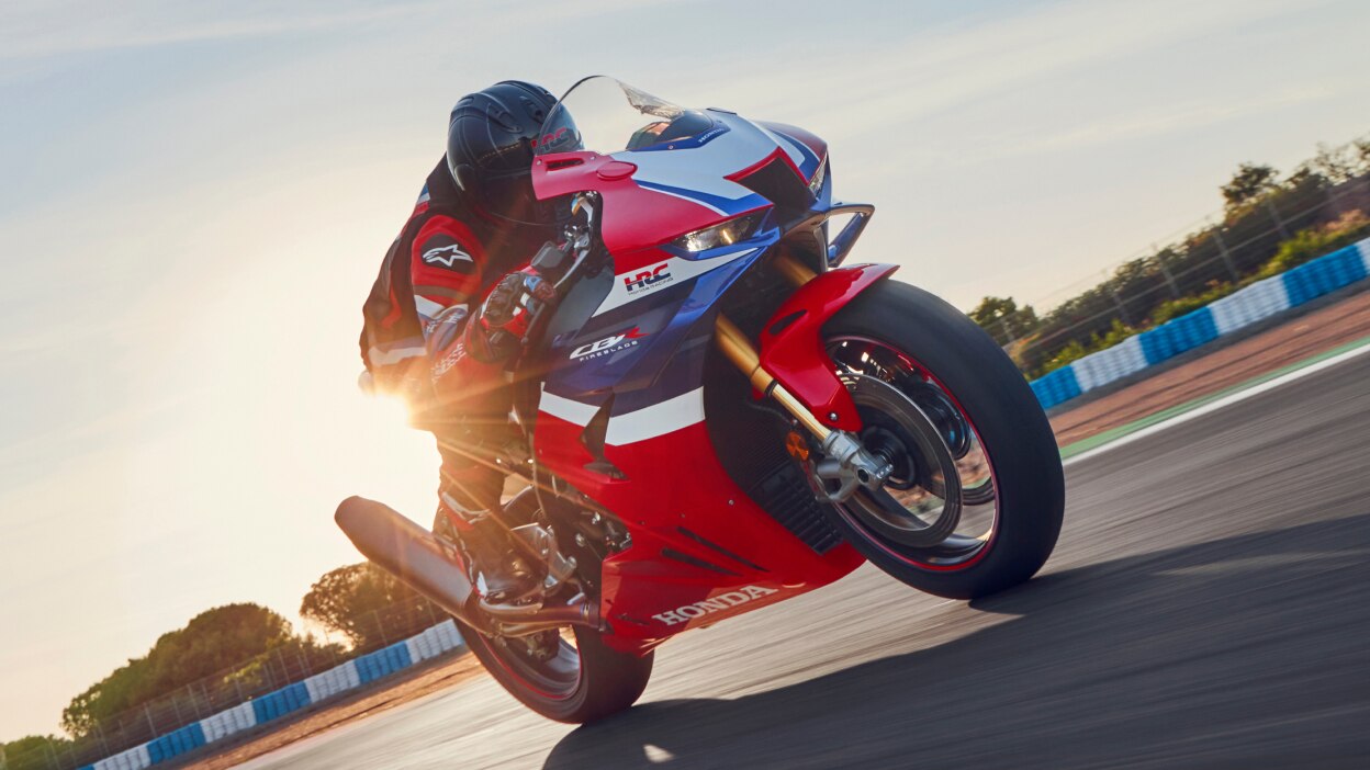 Rider on CBR1000RR-R FIREBLADE SP going straight on track. Sunlight in background.