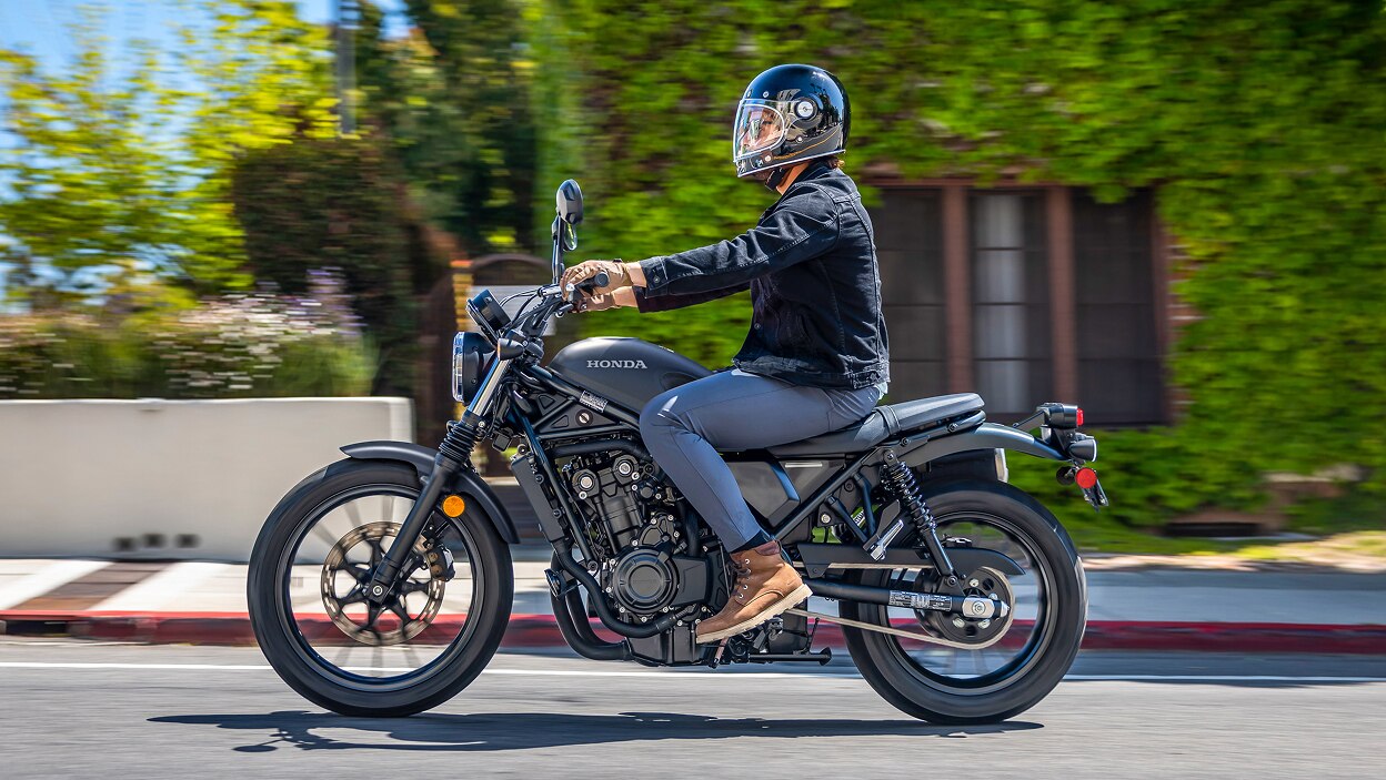 Rider going left on SCL500. House with green leaves attached to walls in background.