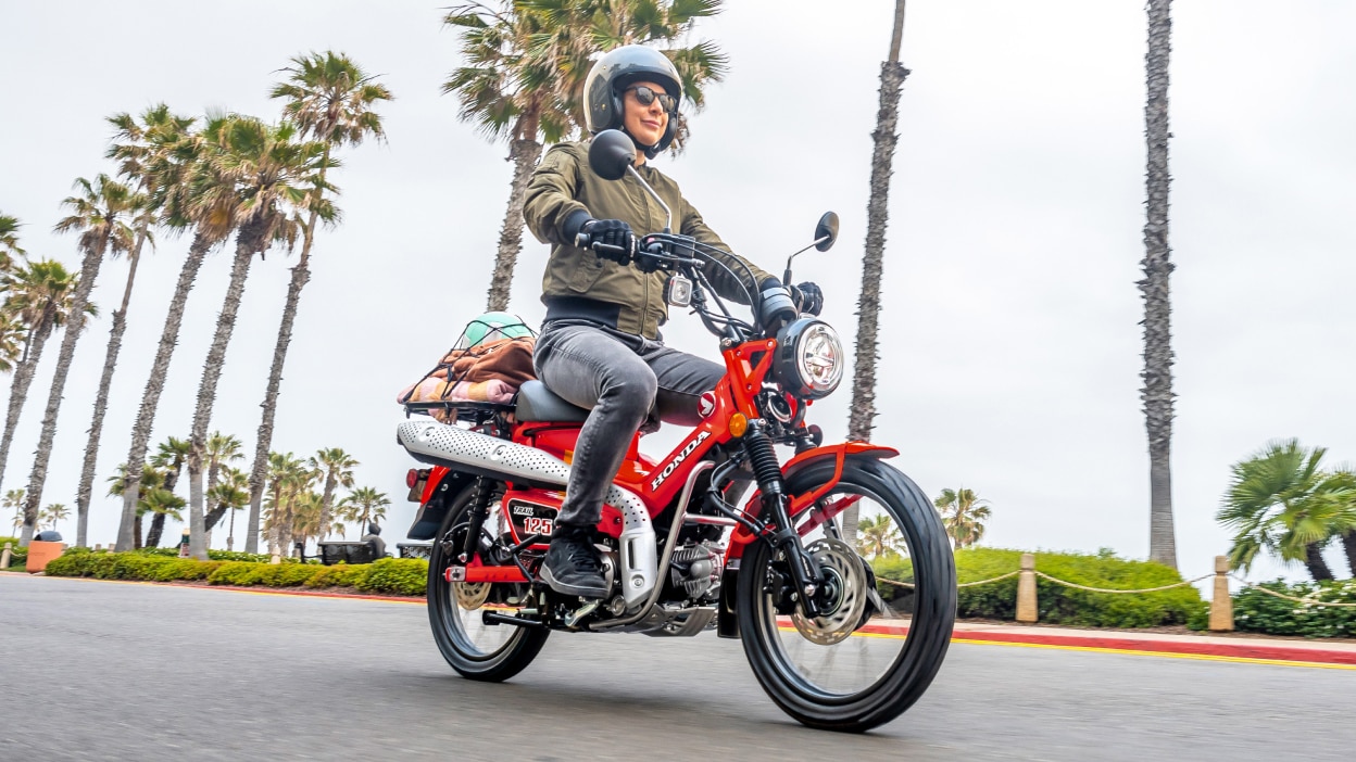 Person on red Trail 125 going right on road. Palm trees in background.