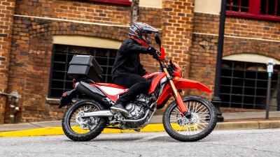 Rider on CRF300L going right. Bricked building in background.