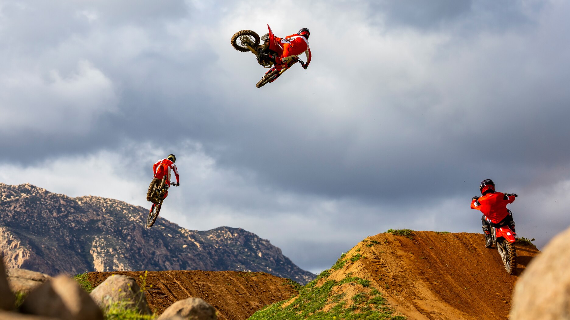 Rear view of riders doing jumps on dirt track.