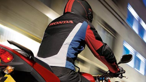 Rear view of a biker wearing a motorcycle jacket and riding a motorcycle at night. / Vue arrière d'un motard portant une veste de moto et conduisant une moto la nuit.