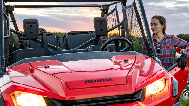 une femme debout à côté d’un VTT Honda rouge/ a women standing next to a red Honda ATV