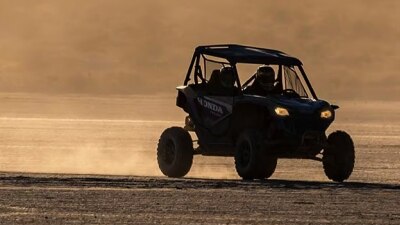 Driver and passenger in Talon. Right angle. Dust from back tires in background.